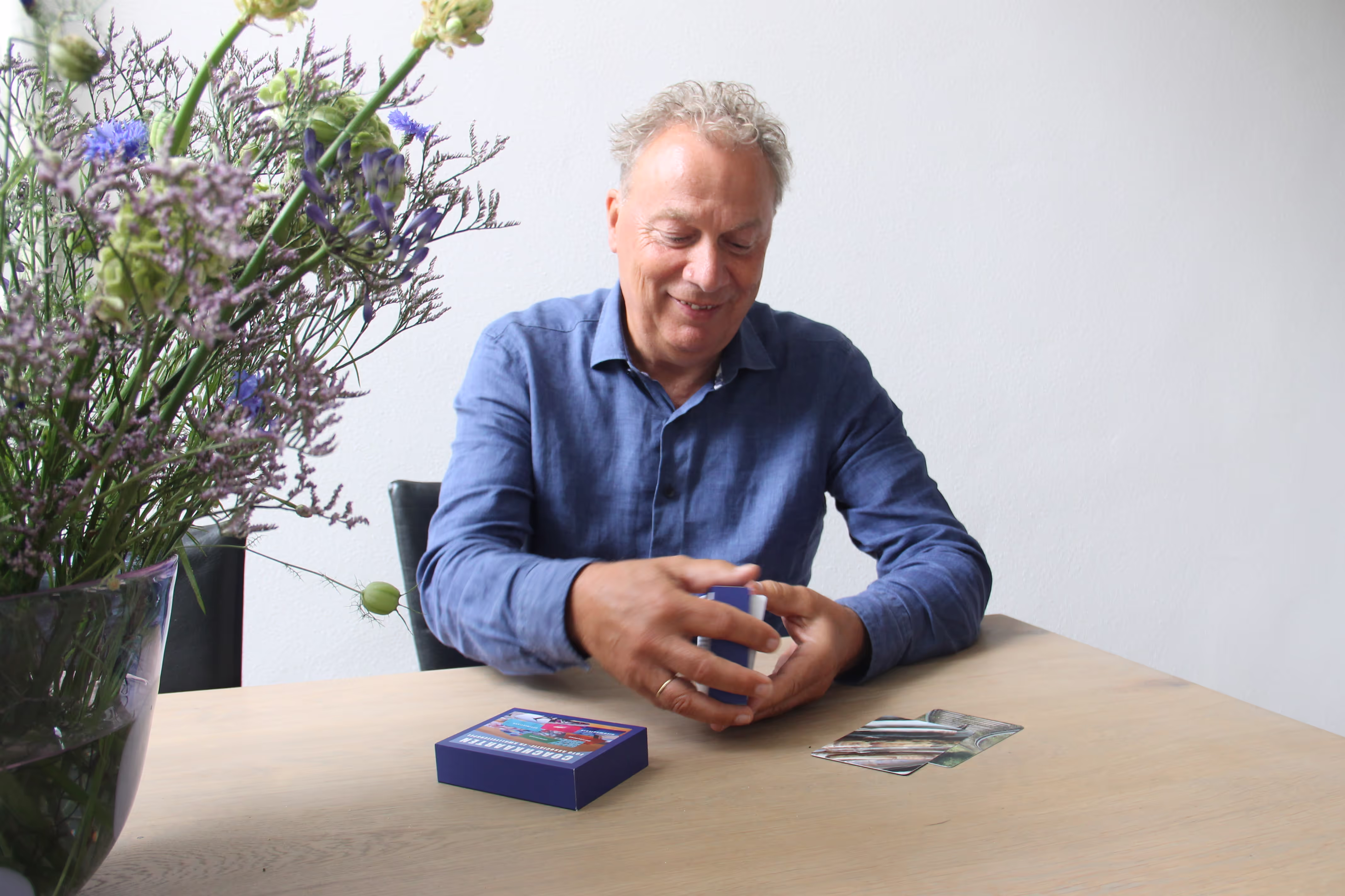 Life coach zit aan tafel met coachingskaarten en een prachtige bloem, klaar om inzichten en begeleiding te bieden.